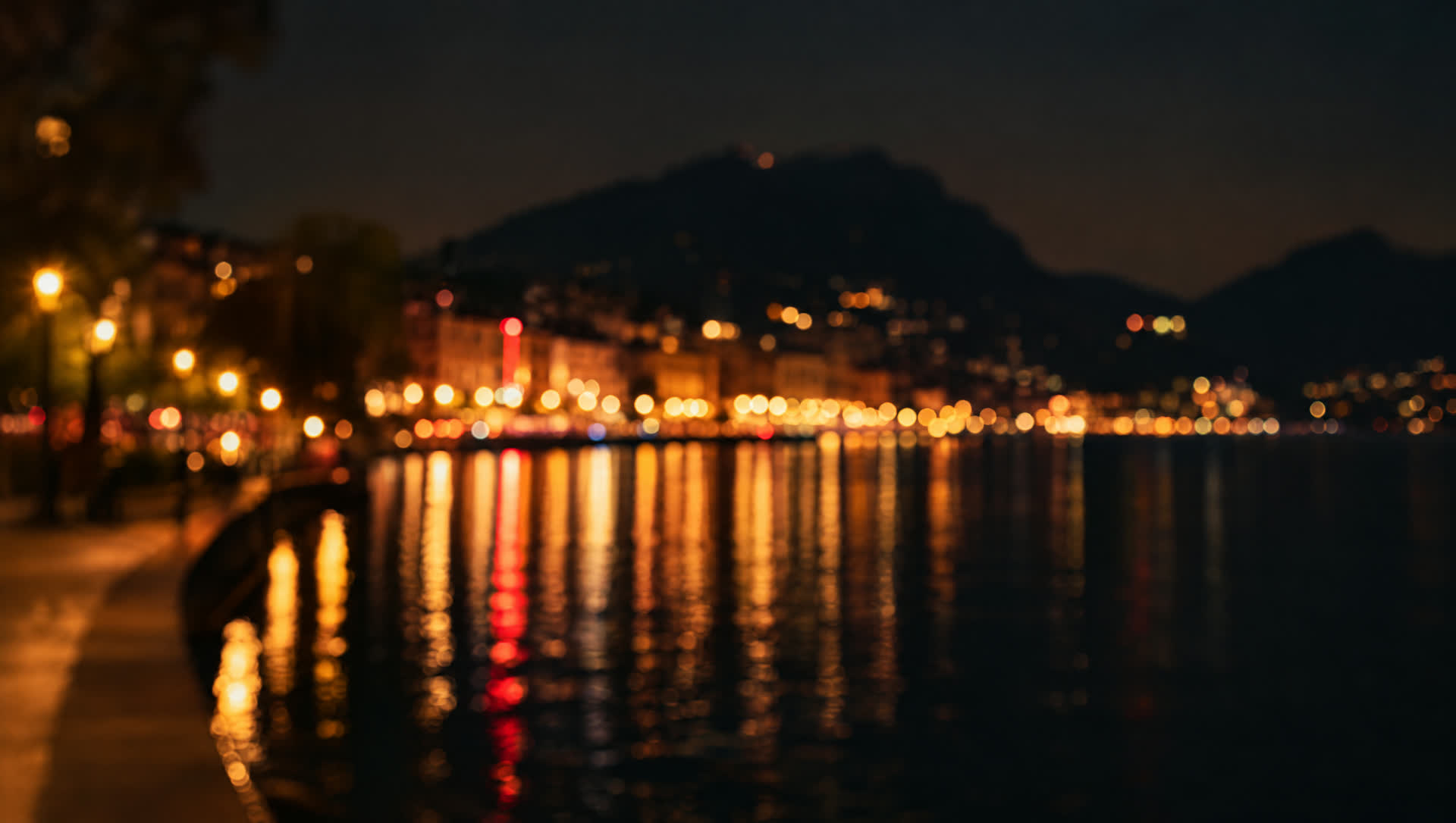 Lugano's lakeside in the evening, with the city lights reflected in the water