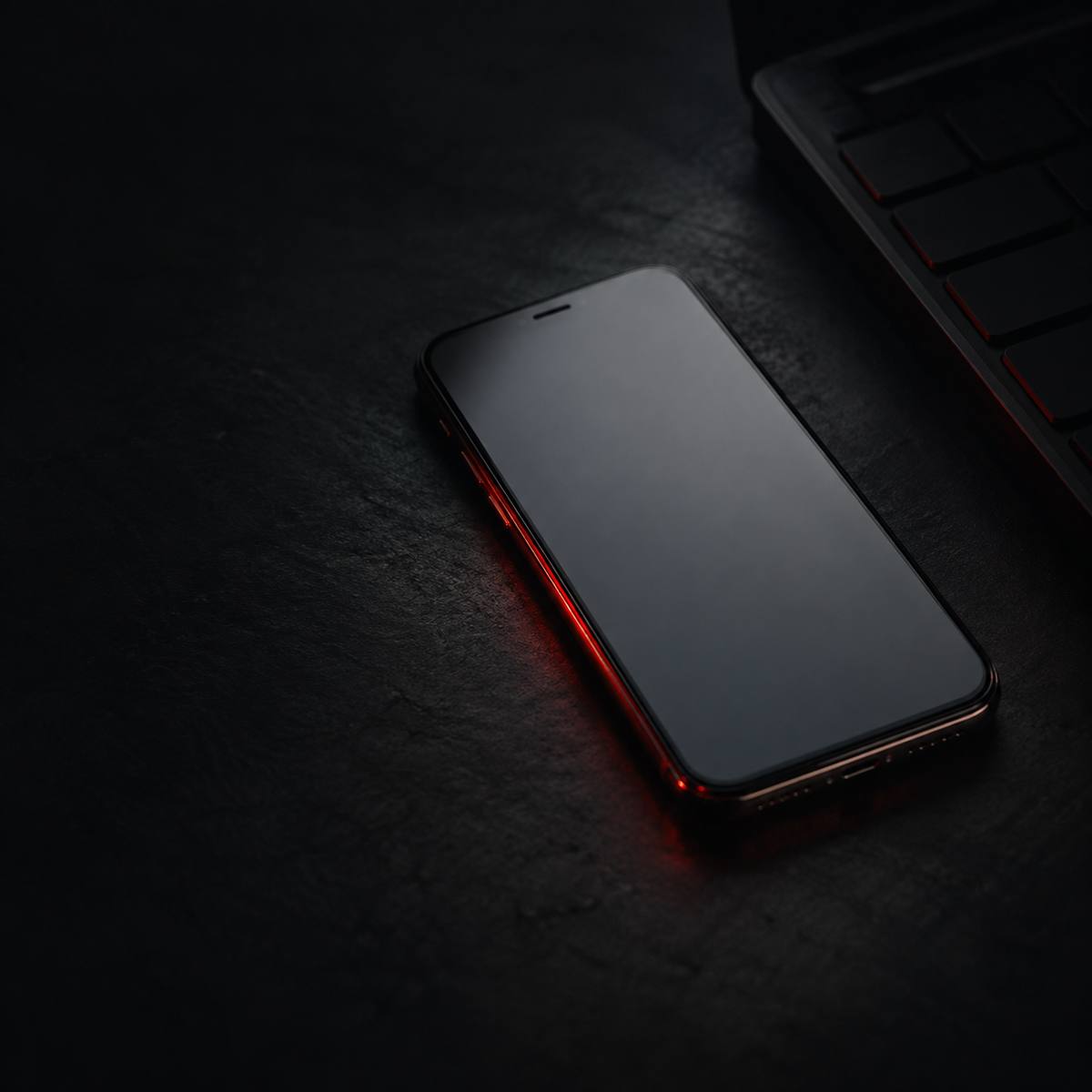 Phone resting on a dark table, next to a laptop