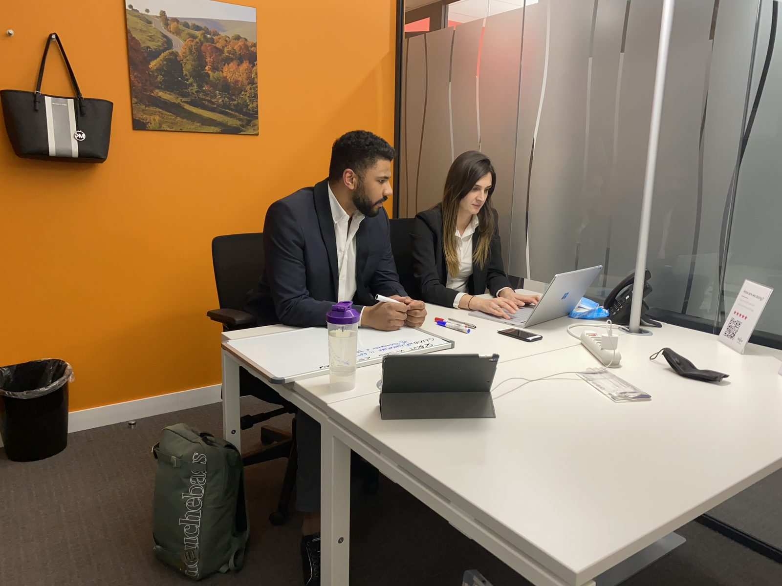 Due persone al tavolo di lavoro con computer portatile, tablet e lavagna